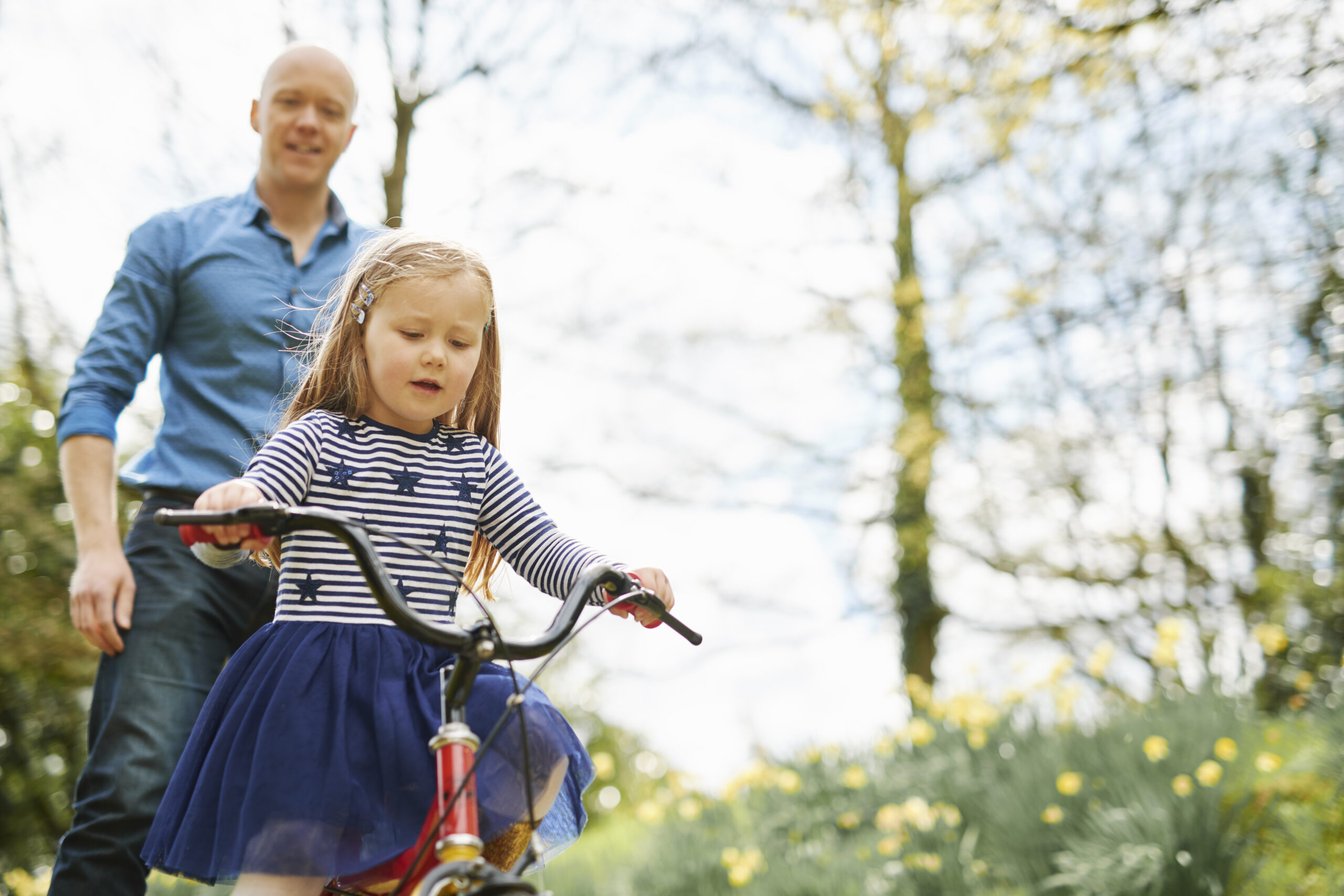 Father teaching daughter to ride bicycle